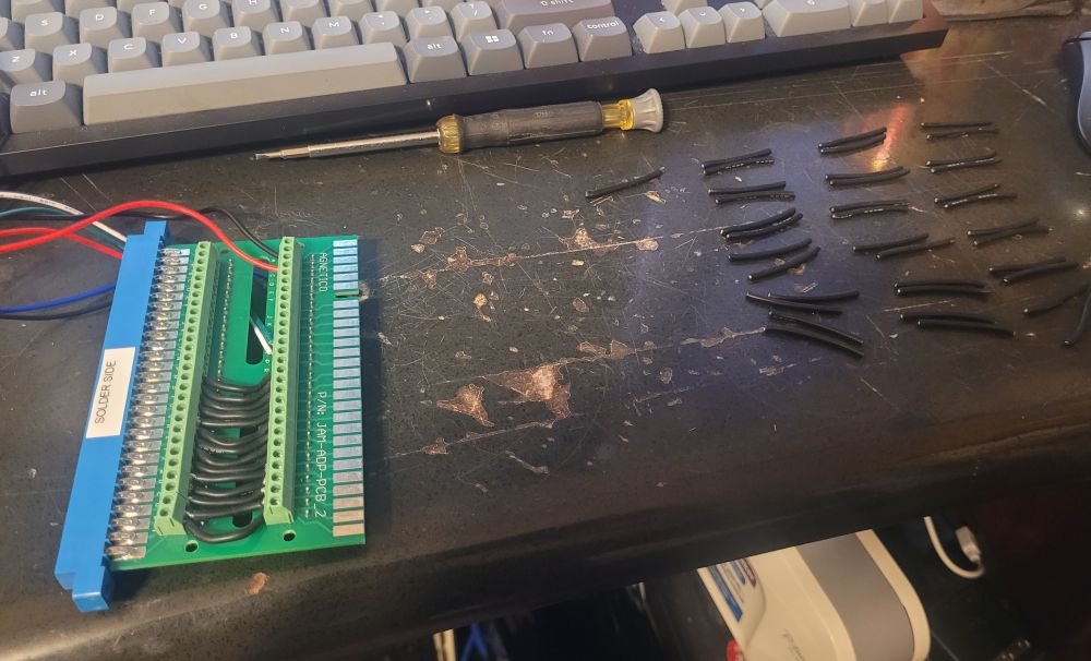 passthrough jamma edge connector being wired manually for an external video signal passthrough. about 14 wires have been connected with several more visible to the right side awaiting stripping 