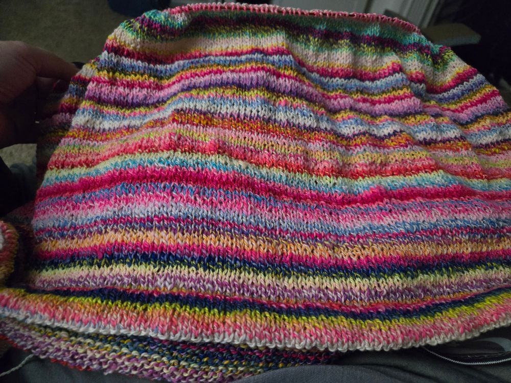 The bottom half of a knitted tshirt in progress.
Colors are a combination of pastel and neon stripes.

