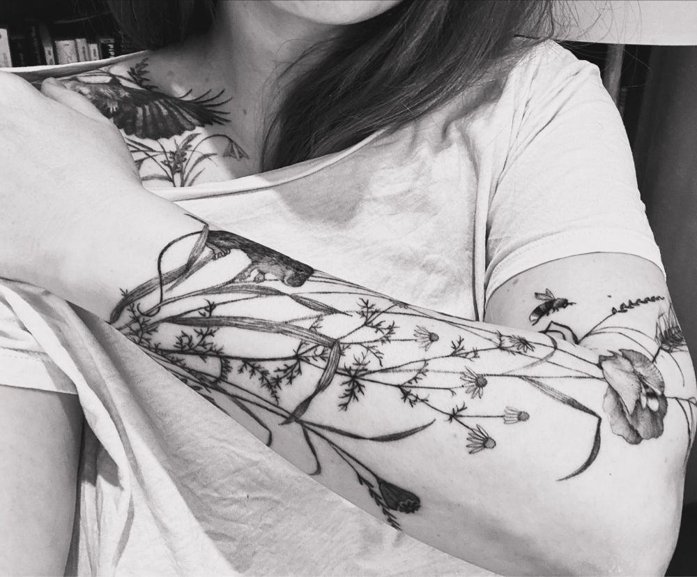 Tätowierter Unterarm. Roggen, Mohn, Maus, Hummel und Kamille.