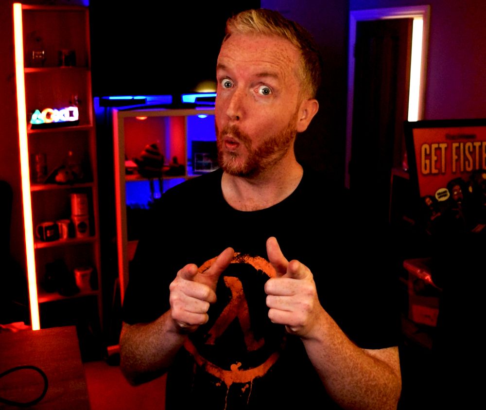 A red-headed man pointing finger guns at the camera with a face of sheer delight and surprise