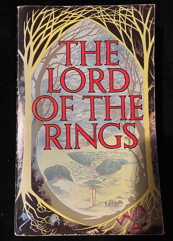 A paperback book. The cover shows a view of a peaceful valley, framed by bare trees and there are strange figures living in the tree roots. The title is "The Lord of the Rings'. No author is listed. They didn't need to.