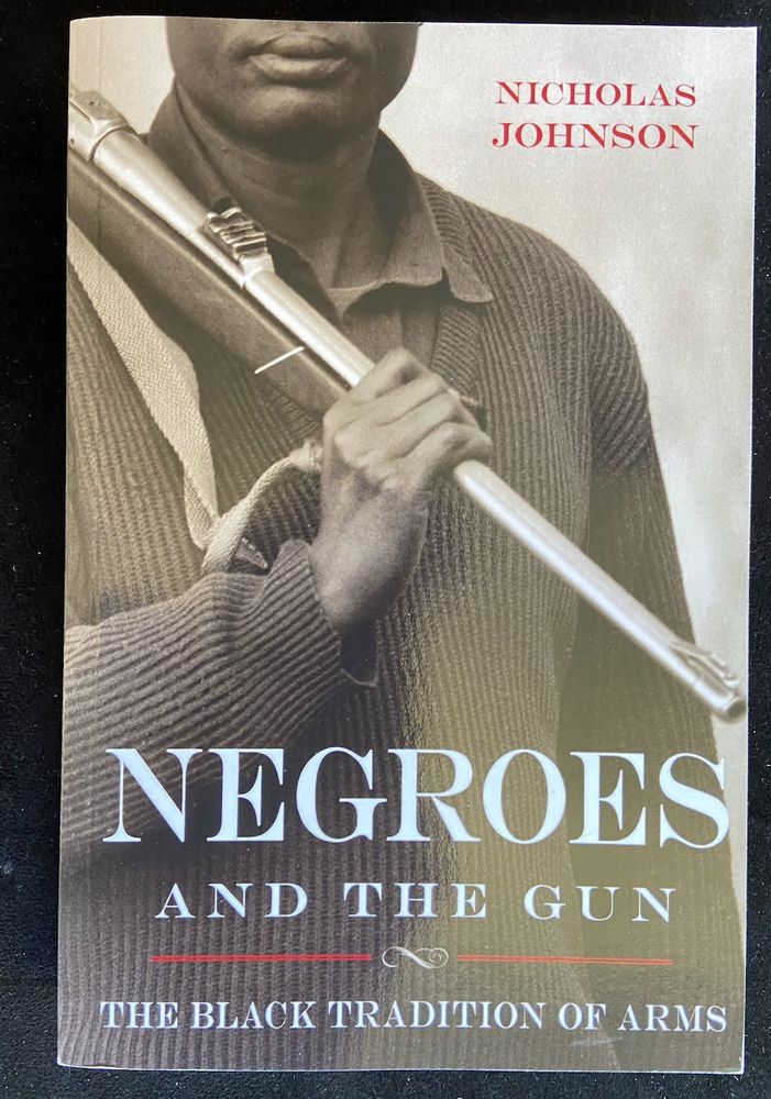 A paperback book. The cover shows a Black man holding a large calibre hunting rifle over his shoulder, his face partially covered. The title is 'Negroes and the gun: The Black Tradition of Arms'. The author is Nicholas Johnson, Professor of Law at Fordham University School of Law.