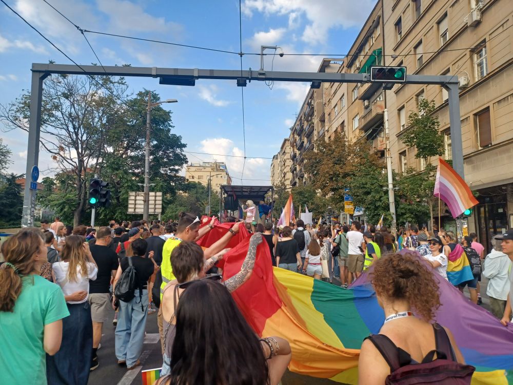 A giant pride flag carried by half a dozen marchers
