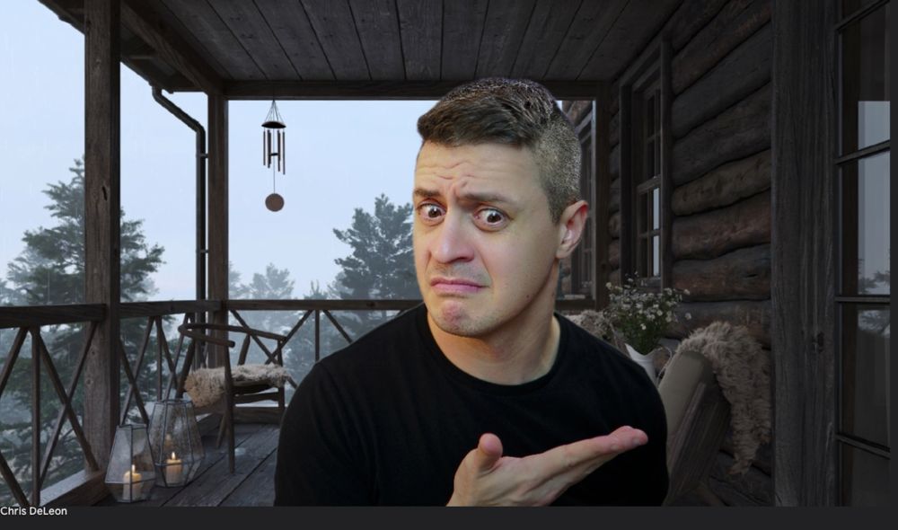 outside of a log cabin in wood setting, me making a silly face holding up my hand.