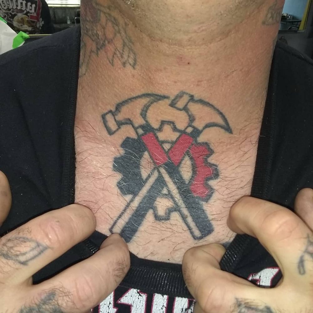 A neonazi with a chest tattoo Showing his hammerskin nation tattoo. Which is a design stolen from pink floyd “the wall)
