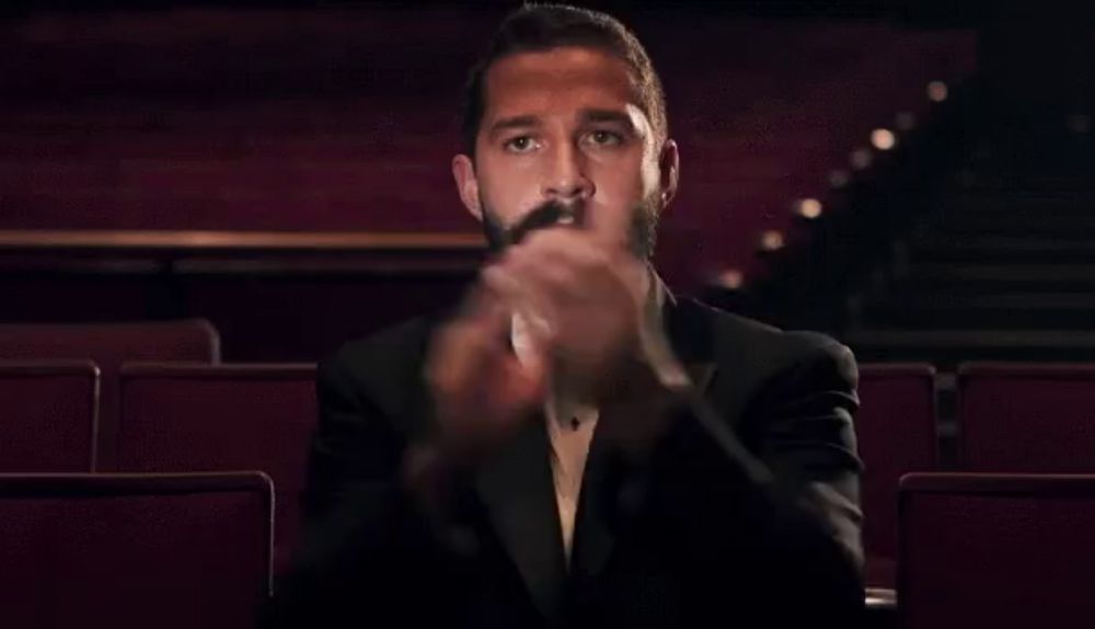 a man in a tuxedo and bow tie applauds in a theater