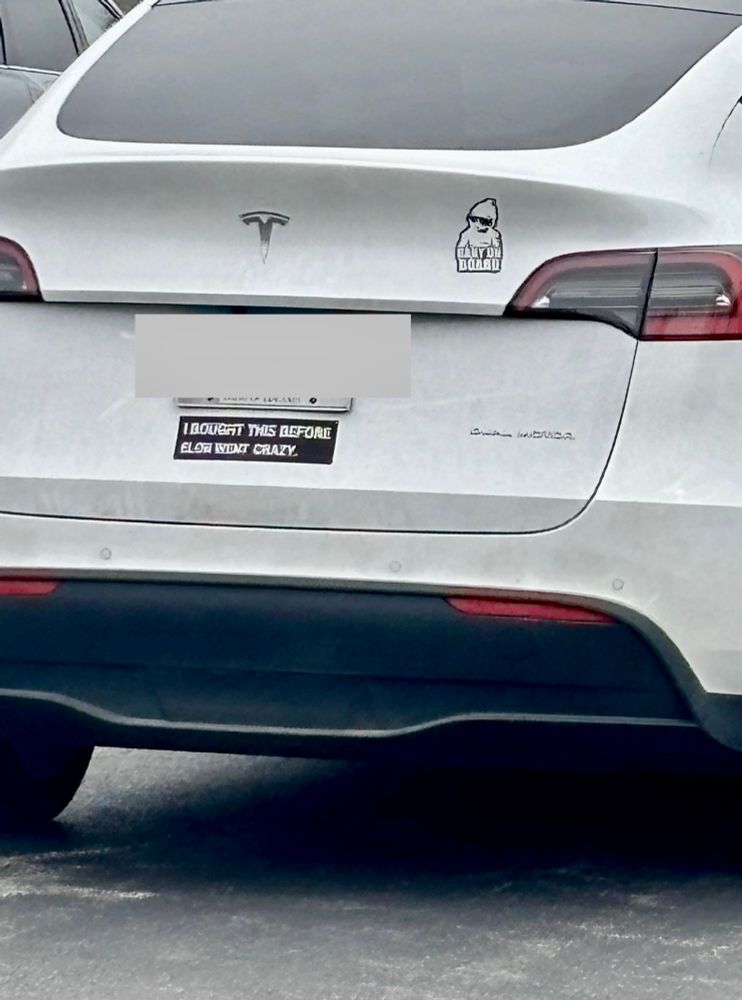 Tesla with sticker stating:  I bought this before Elon went crazy.  