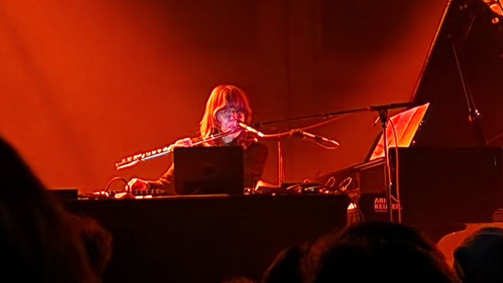 Gezeten achter een laptop in de Lutherse Kerk in Den Haag speelt Japanse muzikant Eiko Ishibashi tijdens festival Rewire (april 2025) fluit terwijl ze met haar rechterhand elektronische effecten toevoegt.