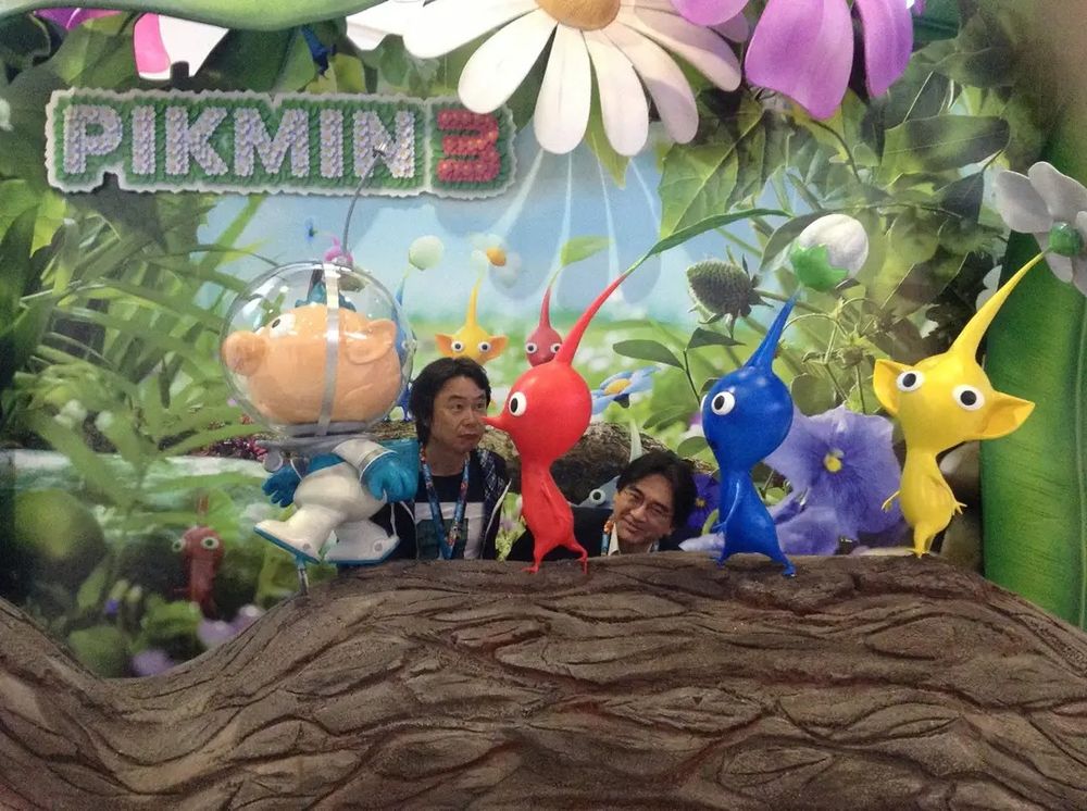 Shigeru Miyamoto and Satoru Iwata amid a human-size Pikmin 3 display at a convention