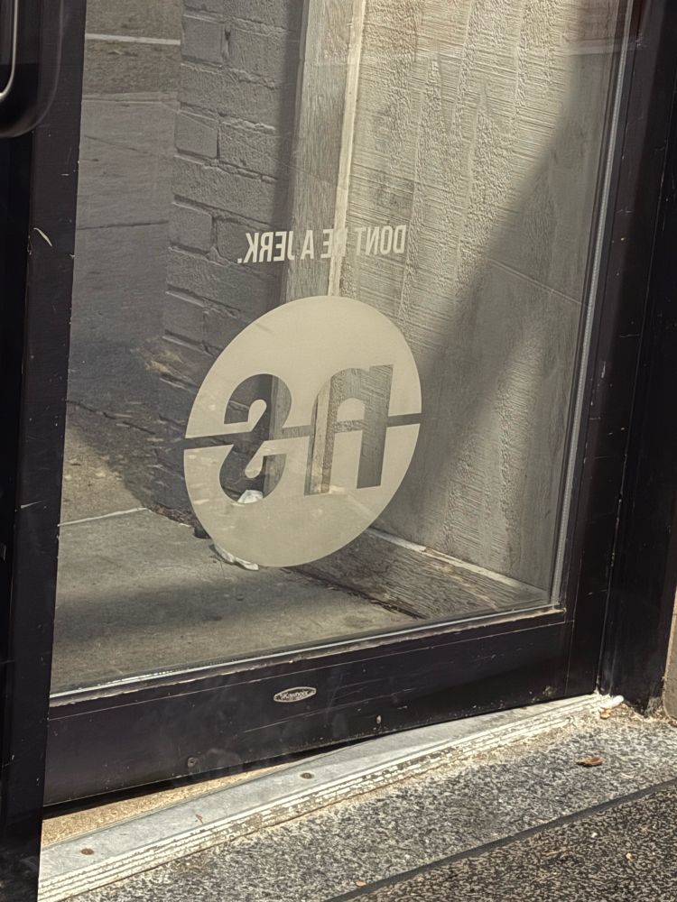 Backside of a bar door that reads “don’t be a jerk”