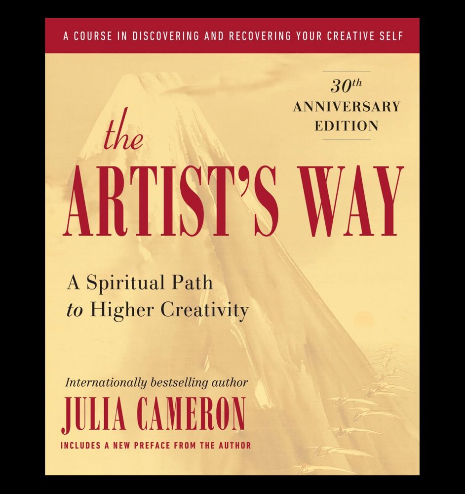 Book cover of Julia Cameron’s The Artist’s Way. 30th anniversary edition. The text is in a deep red on a light goldish background with a mountain faded into the back. 