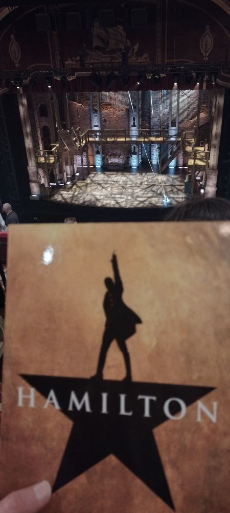 A theatre stage and programme for Hamilton the musical