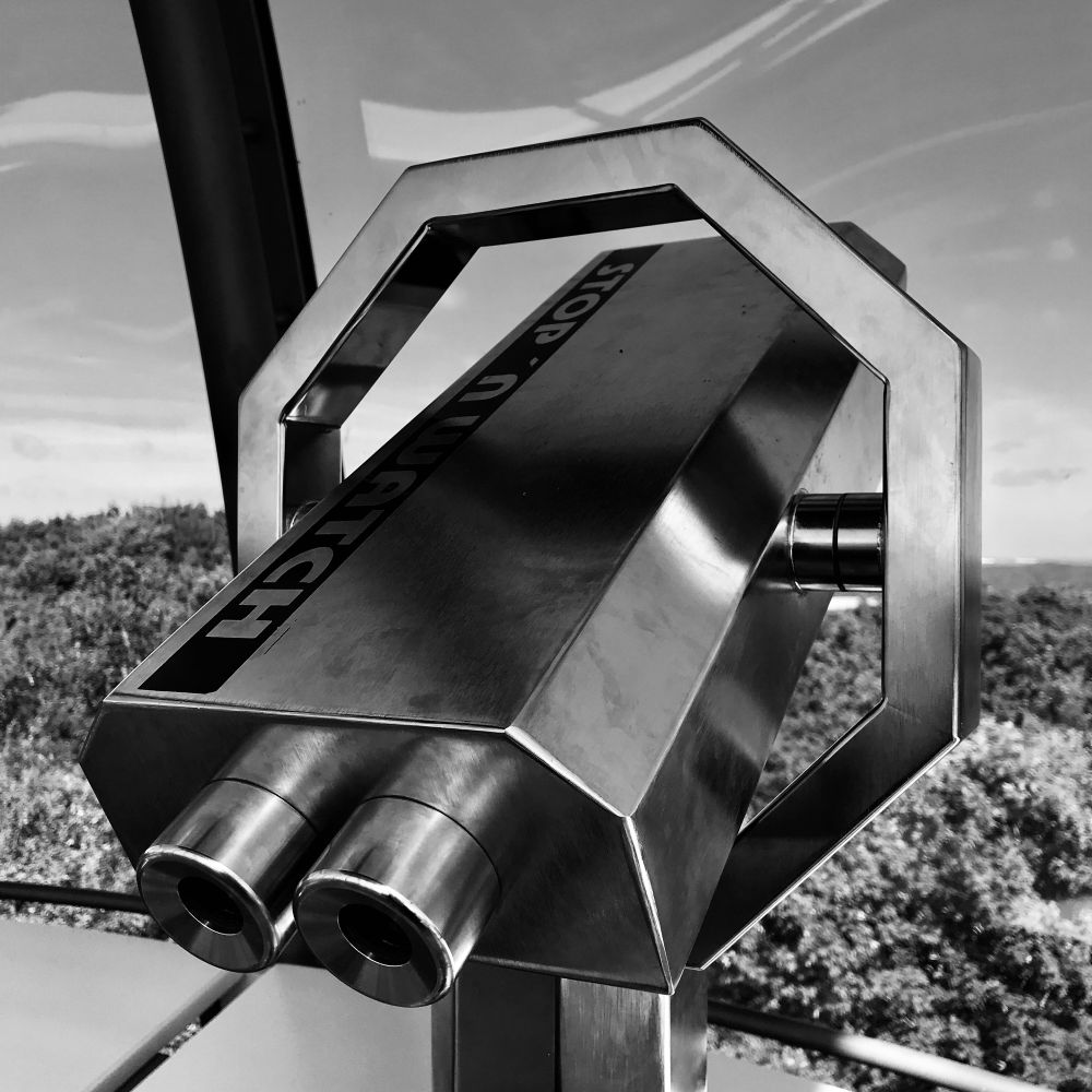 Schwarz-Weiß-Foto (Rohbild) mit einem metallenen Fernglas in der Glaskuppel des Ernst-Moritz-Arndt-Turms auf dem Rugard in der Stadt Bergen auf Rügen. 