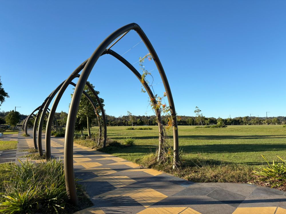 An arbour walkway, a green field, and a clear blue Queensland winter sky - the setting for UniSC Moreton Bay campus.