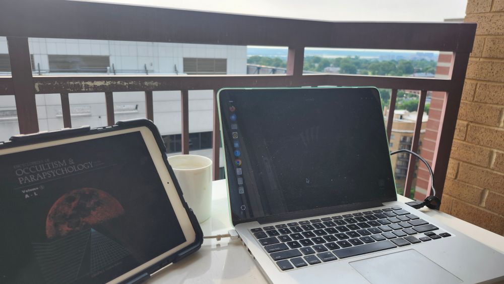 View from a balcony of the Potomac River. Laptop and iPad on a table in the foregrpund.