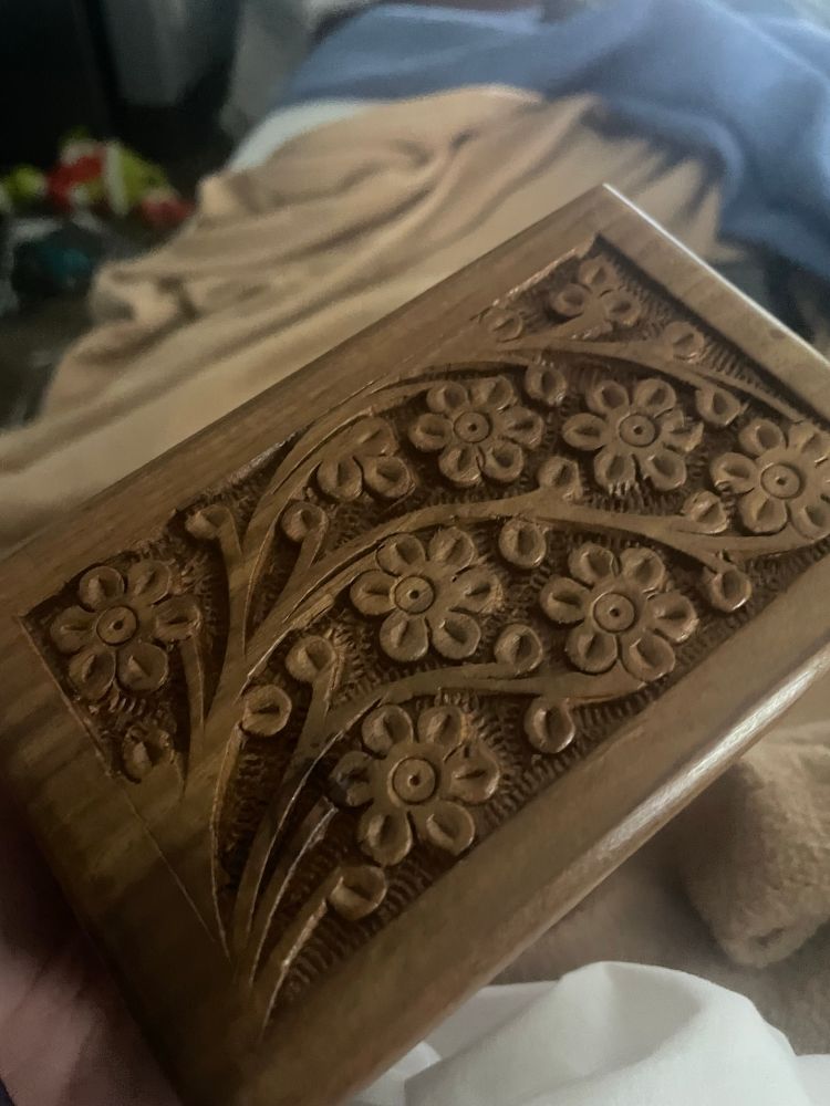 A small wooden box with carved flowers on the top