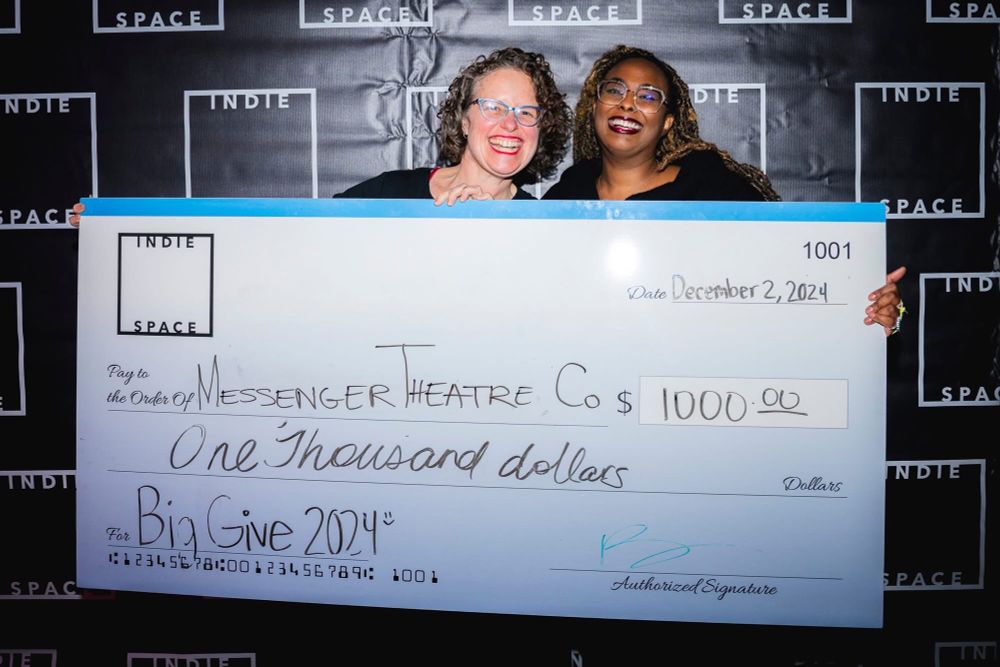 Artistic Director of Messenger Theatre Company, Emily Davis, smiling with India of Indie Space, holding a giant check. 