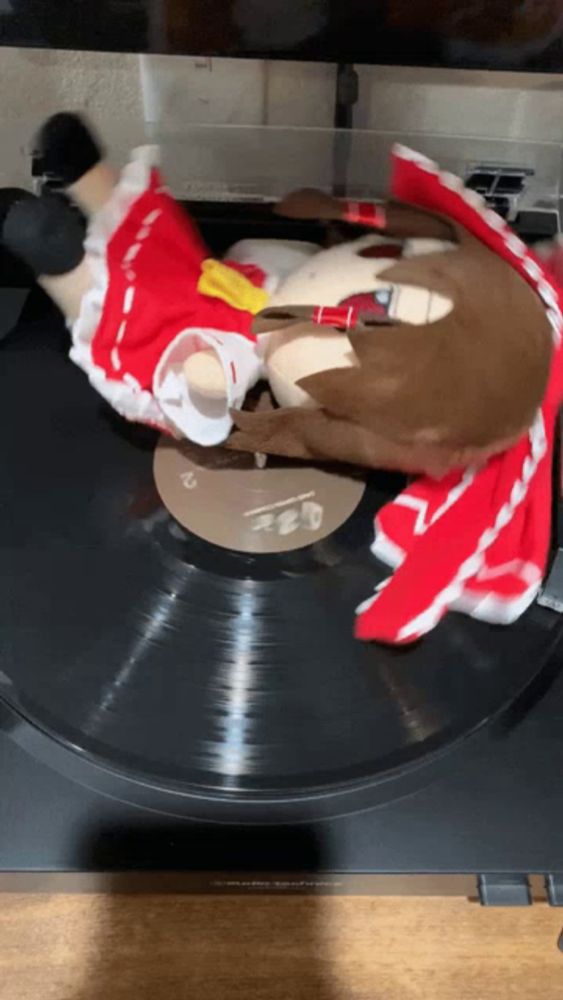 a stuffed animal in a red and white dress is laying on top of a record player