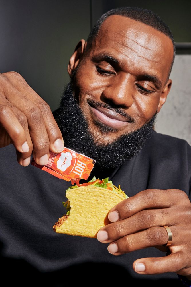 lebron james putting hot sauce on taco. he is very pleased, like a little baby.