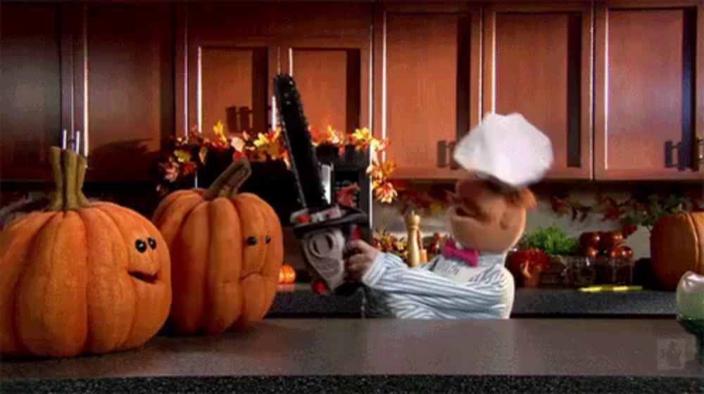 a chef holding a chainsaw in front of pumpkins with faces carved into them