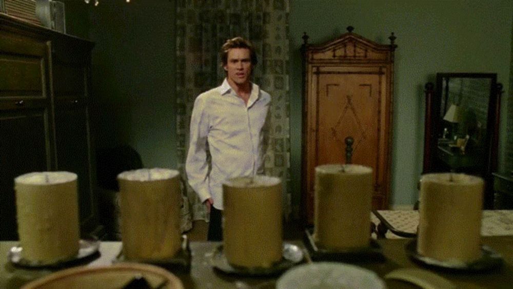 a man in a white shirt stands in front of candles