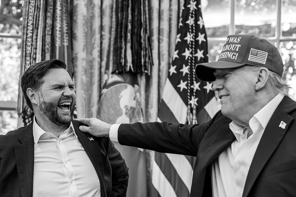 A black and white photo of trump and vance. Trump has his hand on vance's shoulder and vance looks as though he is about to take a bite of of said hand. His canine teeth are elongated.