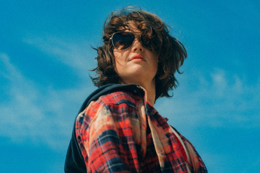 A person in a bikini and flannel poses for the camera.