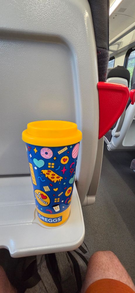 Picture of a colourful travel mug on a train. 