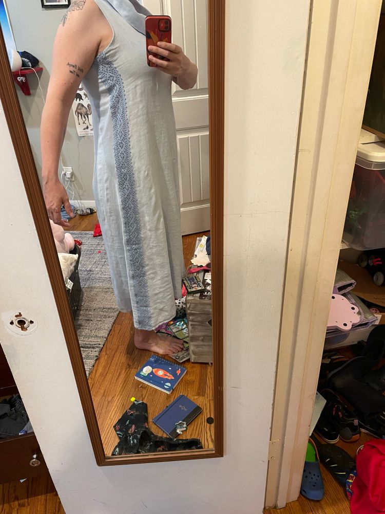 A picture of a woman whose head was cut off by the camera angle. She is wearing the dress which has been altered by sewing the wide lace into the side seams.