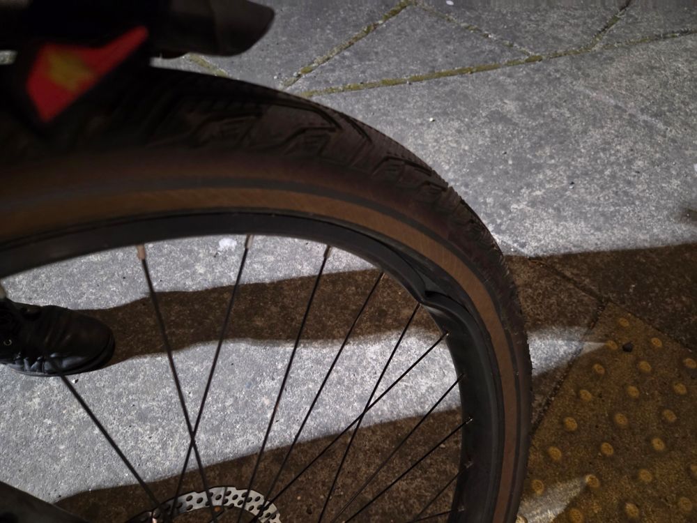 A broken bike wheel, as a result of the previous sudden curb. The rim is completely collapsed by about a half inch, with attached spokes out of tension. 
