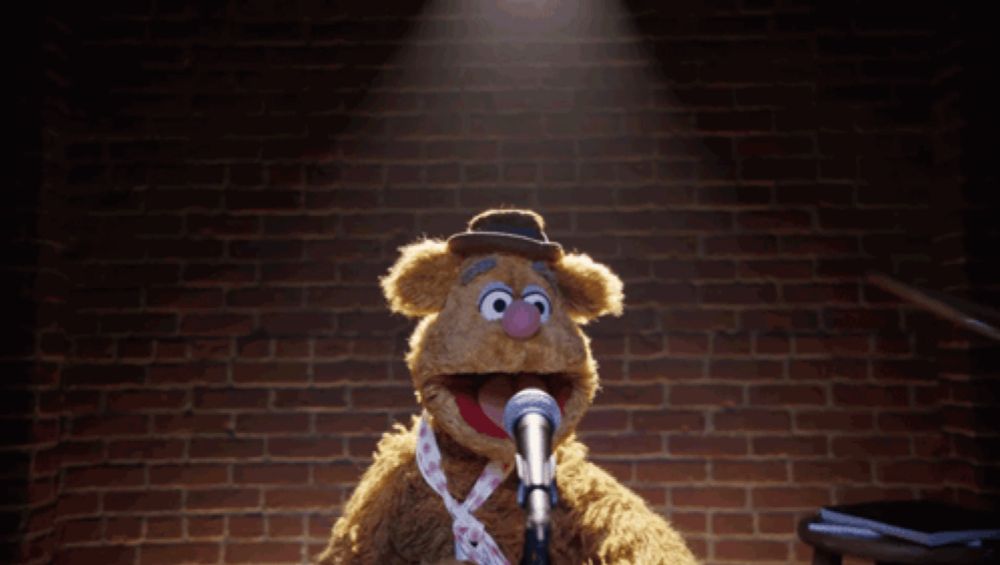 a teddy bear with a hula hoop around its neck is standing in front of a microphone