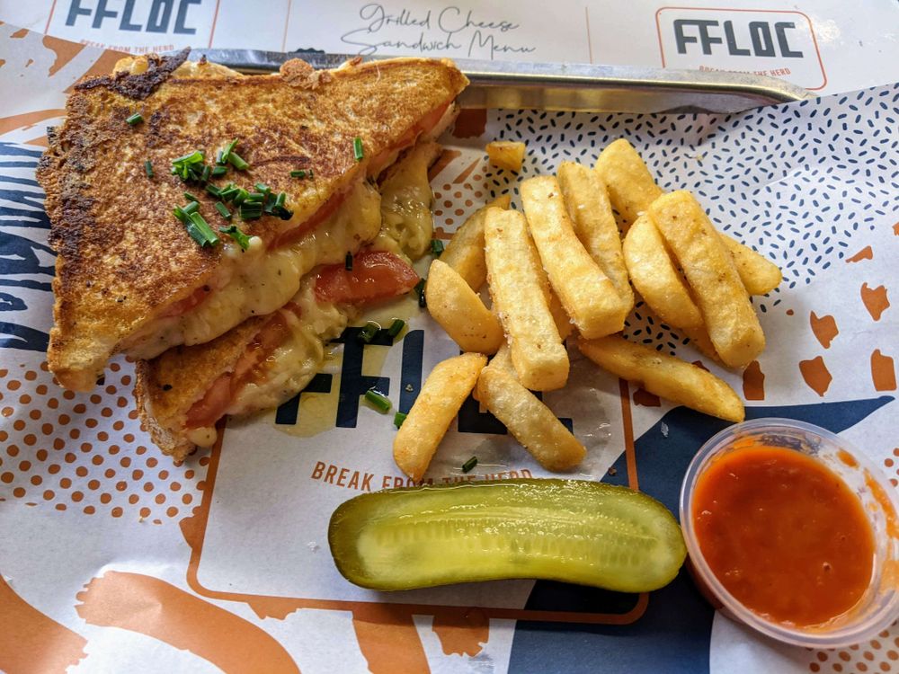 Cheese and tomato toastie with chips, dip and pickle.