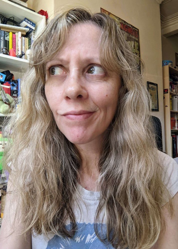 A person with longish light hair that is full of frizz and waves.
