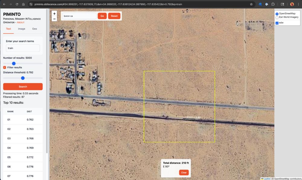 Screenshot of PIMINTO. There is a sidebar on the left showing the search terms, "train", and a list of results. The rest of the page is taken up by a map. In the upper left part of the map is a lookup text field containing "boron ca". The map is showing aerial imagery and is zoomed in to a point just east and south of Boron, CA. There is a yellow box around a portion of the image that seems to contain a train consisting of three cars. There is also a ruler visible, extending along the length of the train. It reads "210 ft - E 93°".
