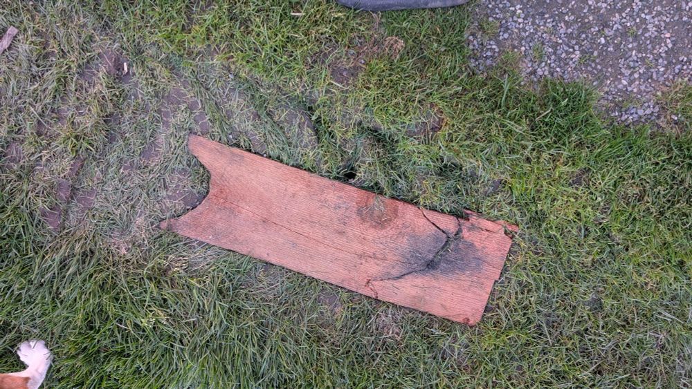 A photo of a wooden plank on green grass.