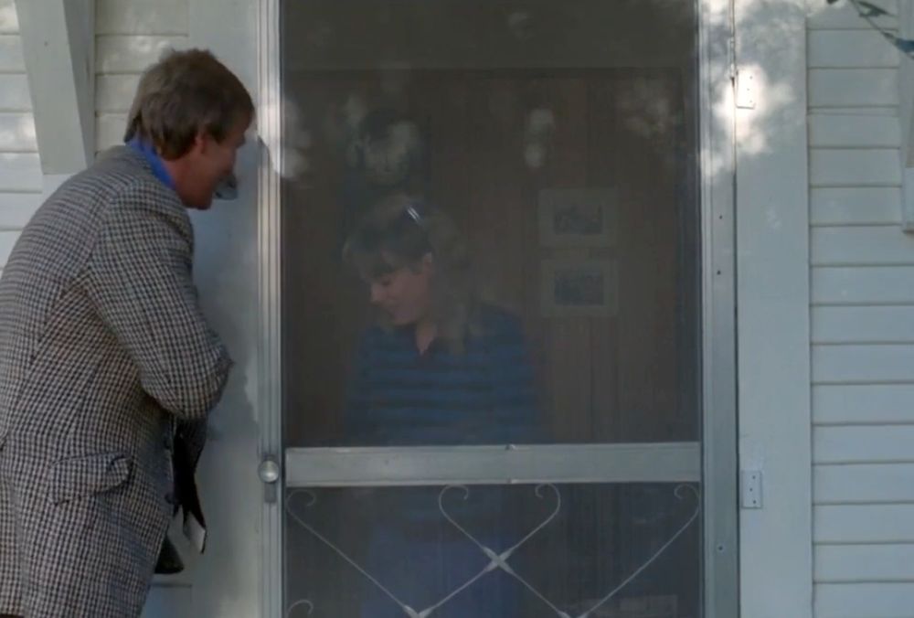 Still frame from a movie with an old metal screen door from the 70s.