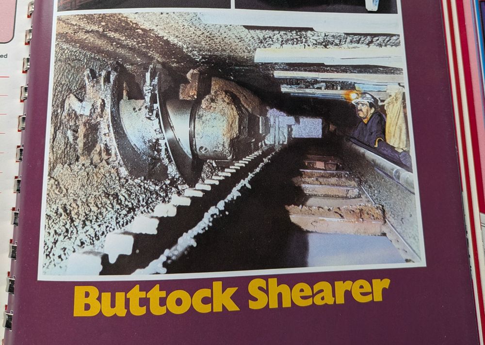 Picture from an old manual depicting a miner underground looking at large mining machine. Underneath, the machine's name:  Buttock Shearer 