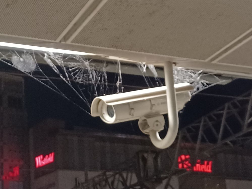 Transport CCTV camera surrounded by cobwebs that are covered in raindrops.