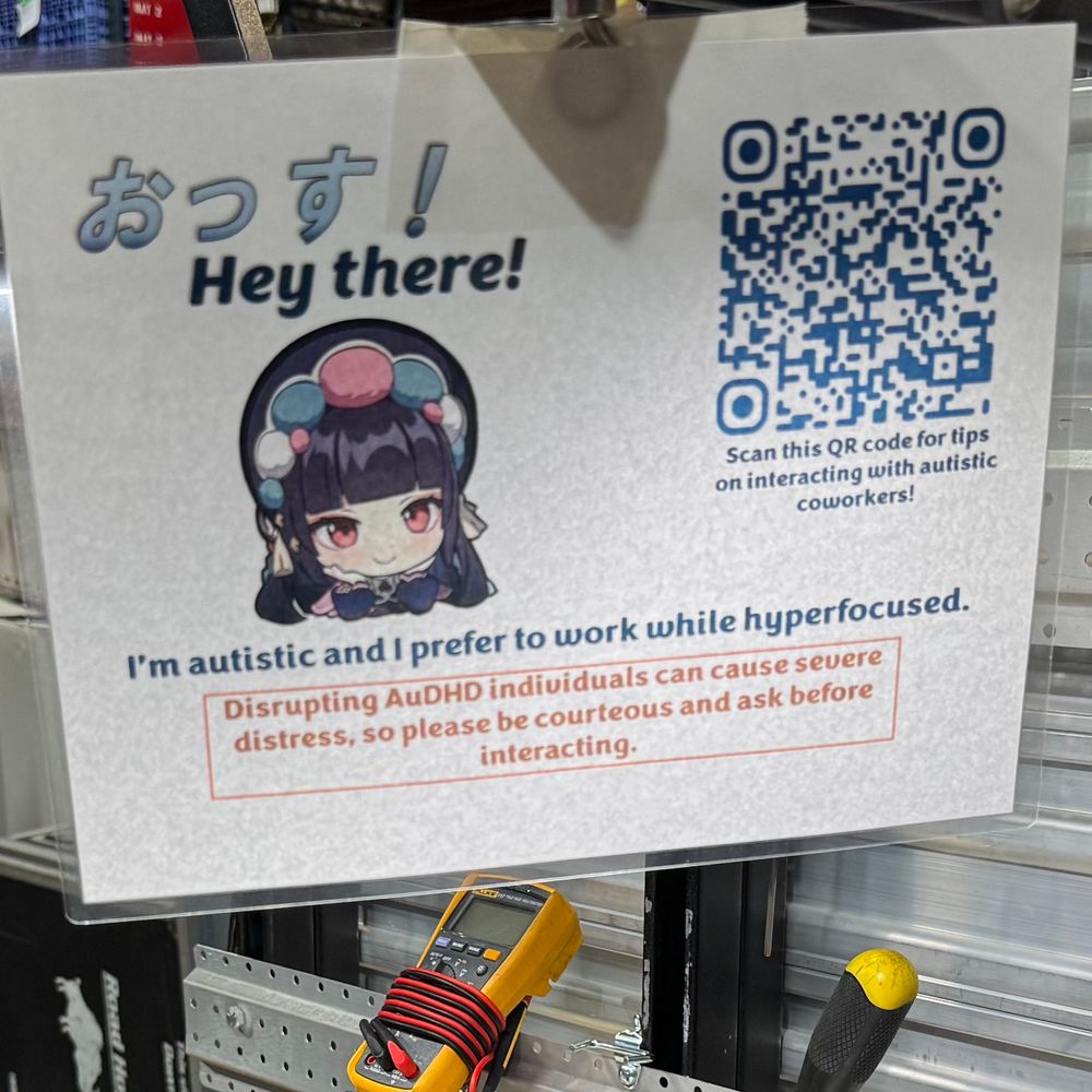 Laminated sign featuring a chibi picture of YunJin from Genshin and a polite notice asking neurotypicals to be more accommodating of autistic coworkers.