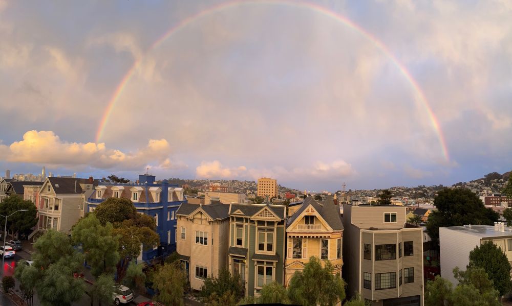 A rainbow in a cloud-filled sky over the San Francisco cityscape