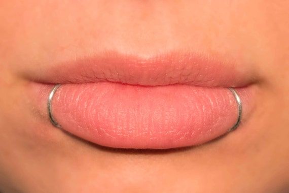 Snake bite piercing: hoop in each corner of lower lip