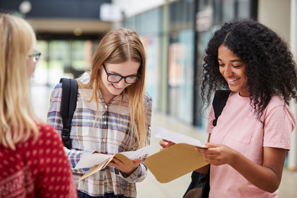 Three students who look happy while they read their exam results