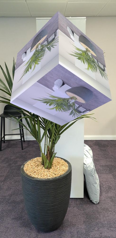 Screenshot of a phone based WebXR session in an office. There is a floating cube placed in the scene that is displaying the raw camera image taken from the device’s camera.