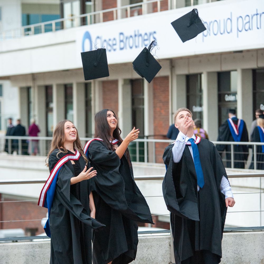 3 grads throwing their caps in the air