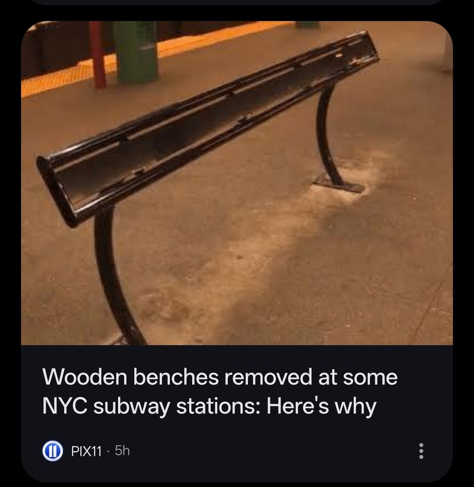 An image of a standing, lean-"bench" in the middle of an NYC subway platform, where there is evidence that a larger wooden bench where one could actually sit was removed. The title under the image screenshot says "Wooden benches romced at some NYC subway stations: here's why - PIX11" 