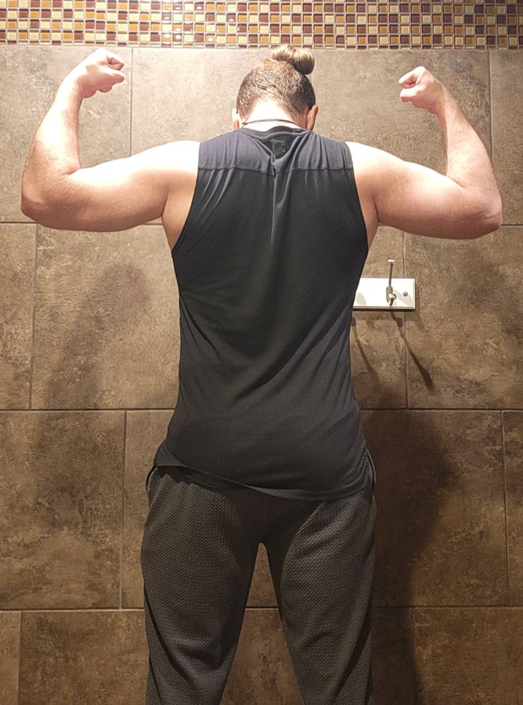 I'm doing a back facing double bicep pose showing off my shoulders, biceps, and triceps. I'm wearing a black sleeveless compression shirt.