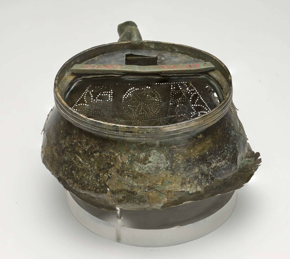 Photo showing the strainer inside the objects; it's a large plate covering the spout area, decorated with pierced geometric-floral design.