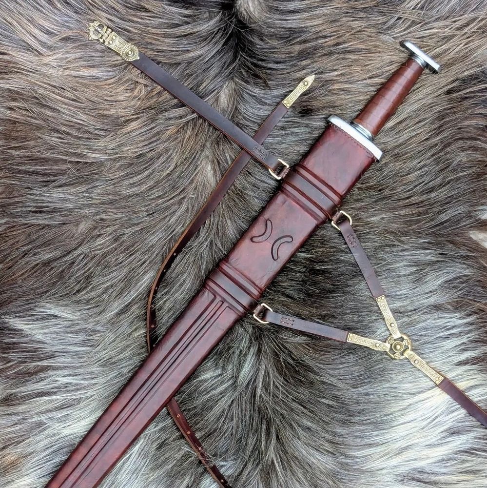 Photo of decorated leather scabbard and Hiberno Norse sword fittings. The sword and belt are laying on a grey tone goat skin. 