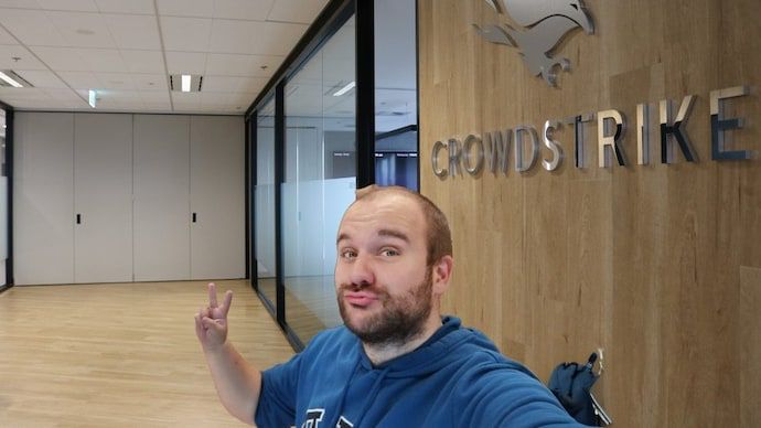 Guy giving peace sign in front of Crowdstrike office sign 