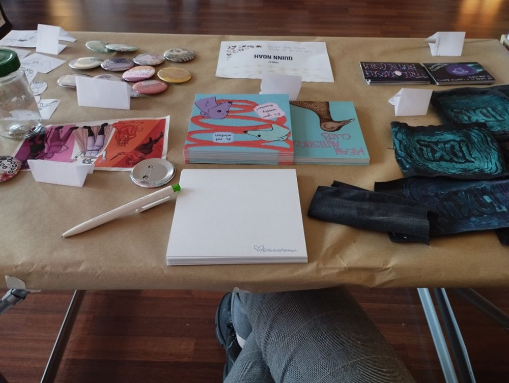 Foto von einem in Packpapier gepackten Tisch, auf dem Buttons, Sticker, Prints und Patches liegen.